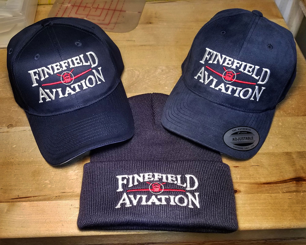 Baseball caps and knit caps with Finefield Aviation's logo embroidered on the front