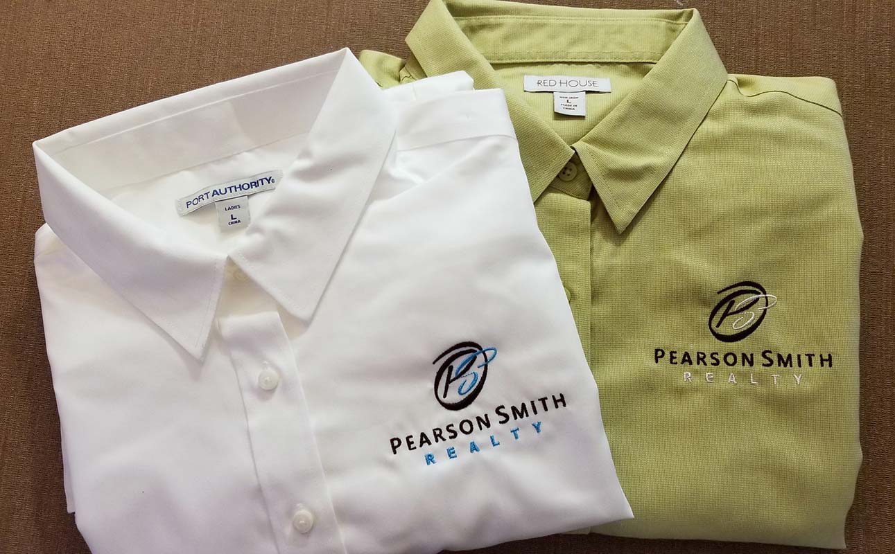 Two shirts with Pearson Smith Realty logo embroidered on left chest