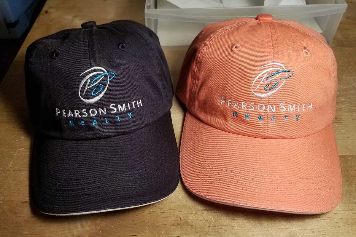 Two custom embroidered baseball caps for Pearson Smith Realty