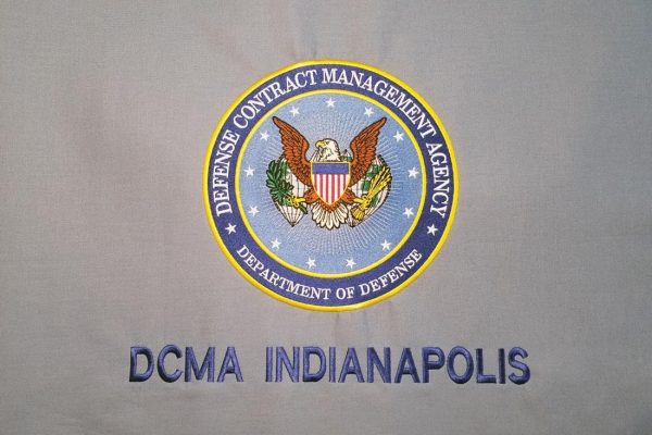 Department of Defense, Defense Contract Management Agency Seal embroidered in blue and gold on a gray background with DCMA Indianapolis embroidered in matching navy blue beneath it.