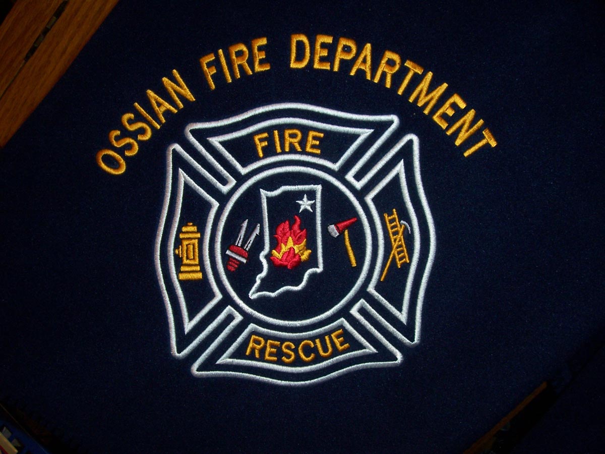 Navy blue fleece blanket embroidered with the words Ossian Fire Department in gold above the OFD shield in red, gold, and white.